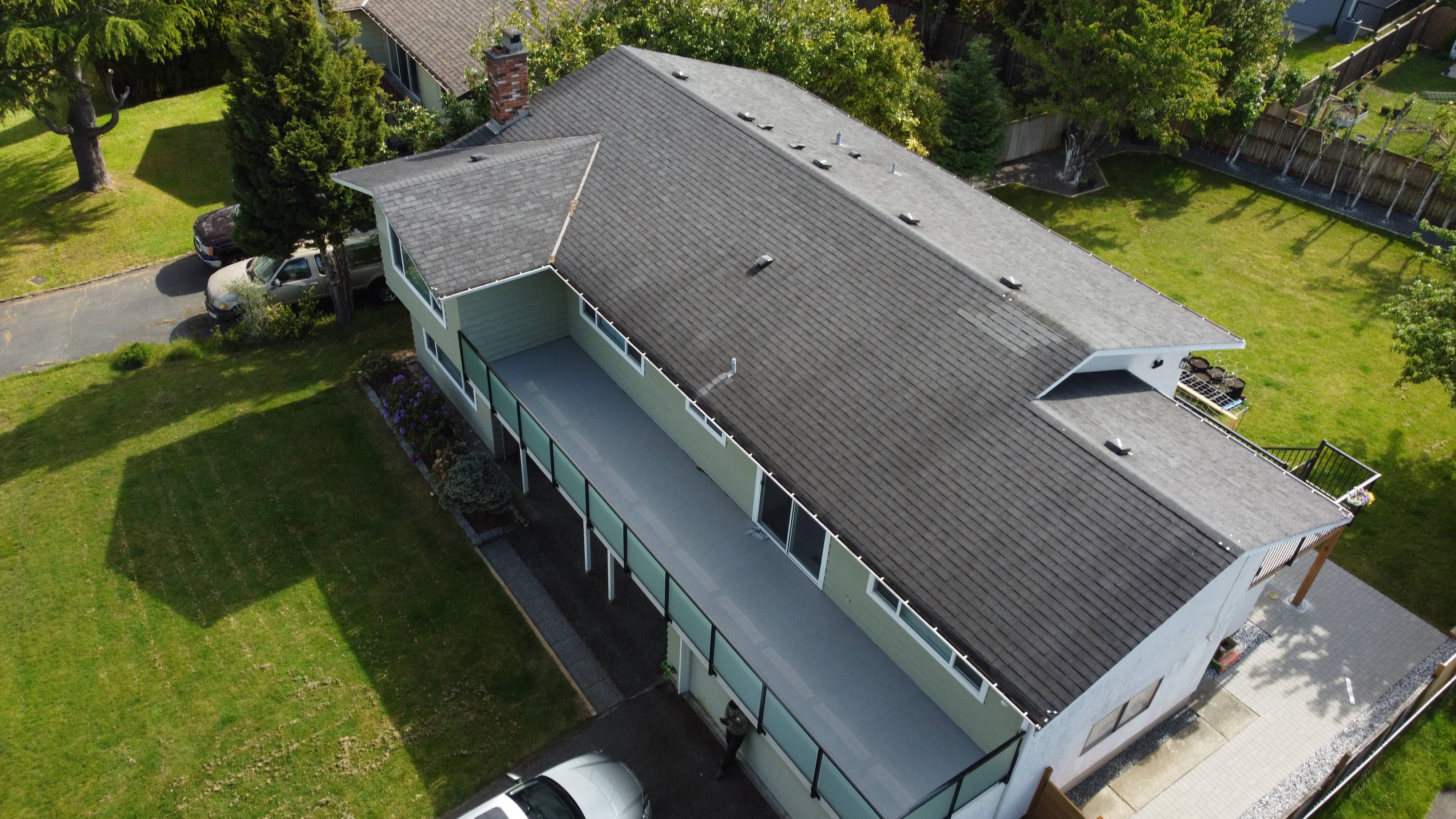 Before - aerial view of green two-storey home with worn dark grey shingles in Victoria BC