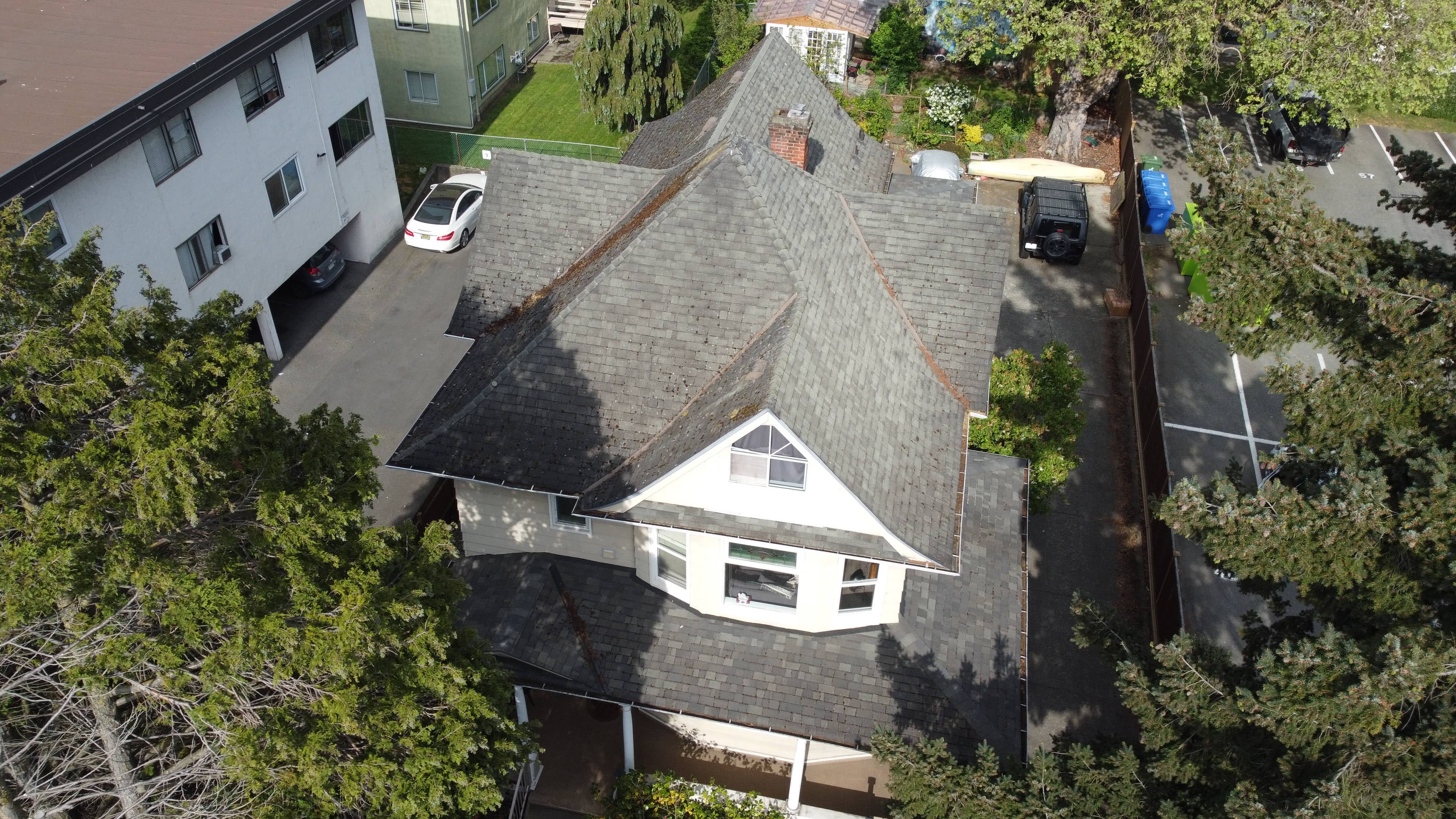 Before - aerial view of character home with aged dark grey shingles and brick chimney in Victoria BC